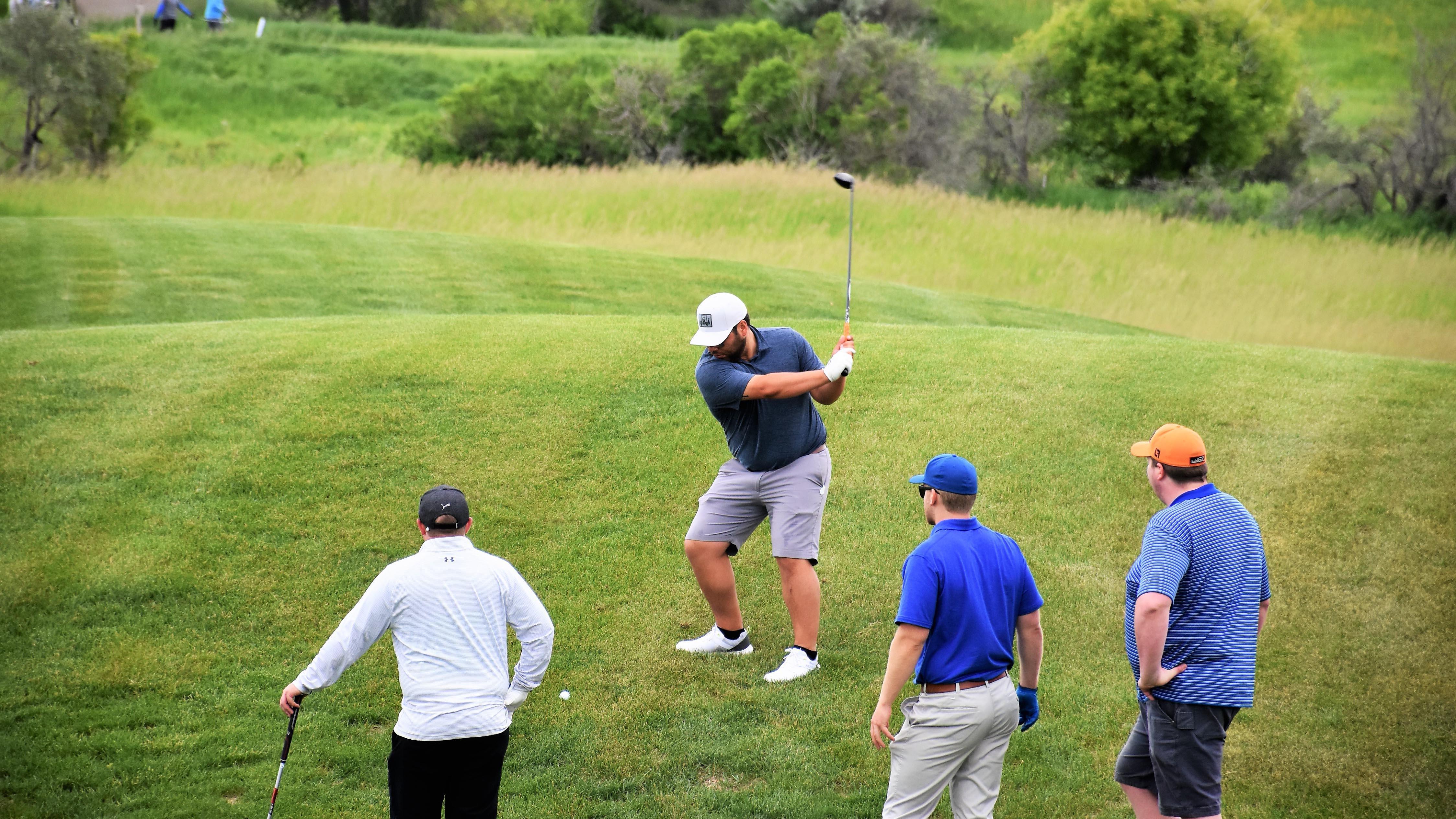 Four men golfing on a green golf course.